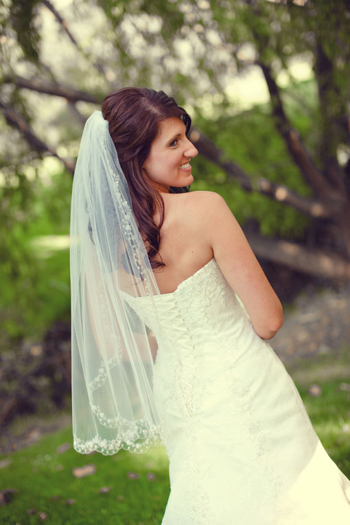 Smiling bride in strapless gown and veil outdoors