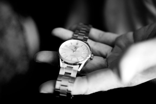 Black and white shot of a silver wristwatch on a hand