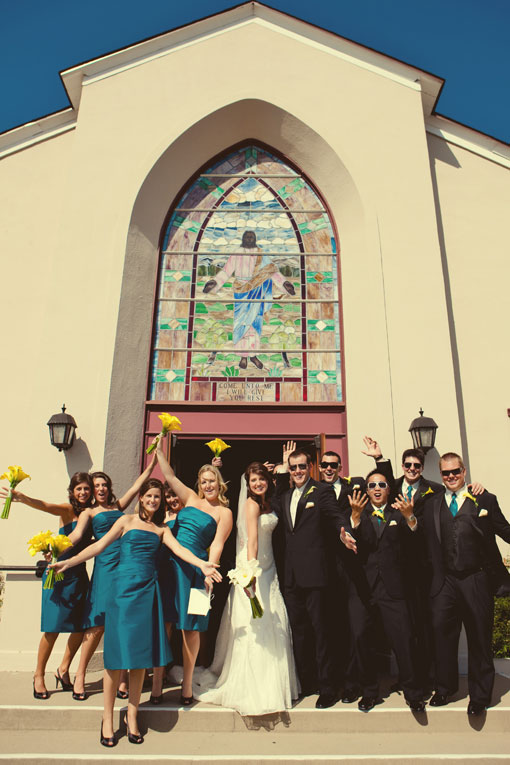 Wedding party celebrates outside church with stained glass
