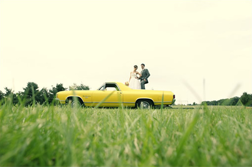 Bride and groom pose on a vintage yellow El Camino
