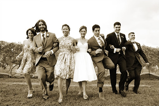 Wedding party joyfully running together in sepia toned photo