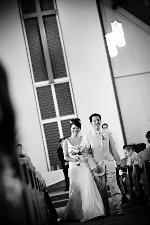 Black and white photo of bride and groom walking aisle