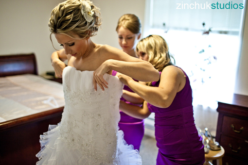 Bride getting help with wedding dress from bridesmaids