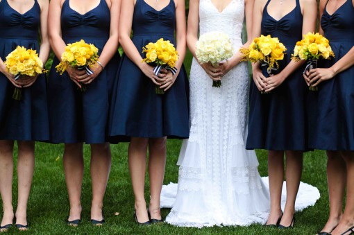 Bride with bridesmaids, navy dresses and yellow bouquets