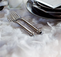 Elegant silverware and plates set on a feathery surface