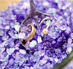 Wedding rings in a spoon on a bed of purple crystals