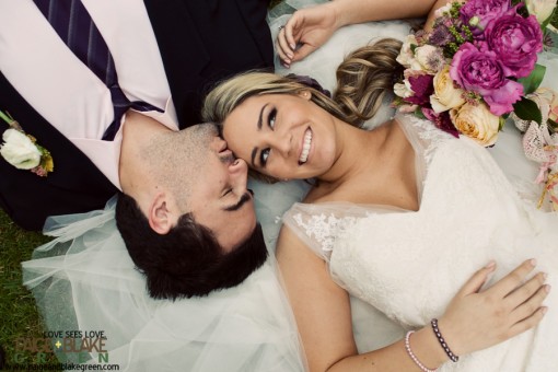 Happy bride and groom lie together with flowers on wedding day