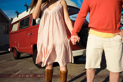 Couple holding hands with a red van ready for vacation