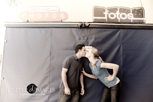 Loving couple share a kiss under photo signs and blue curtain background