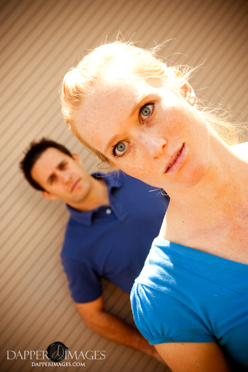 Blonde woman with blue eyes and man behind her posing