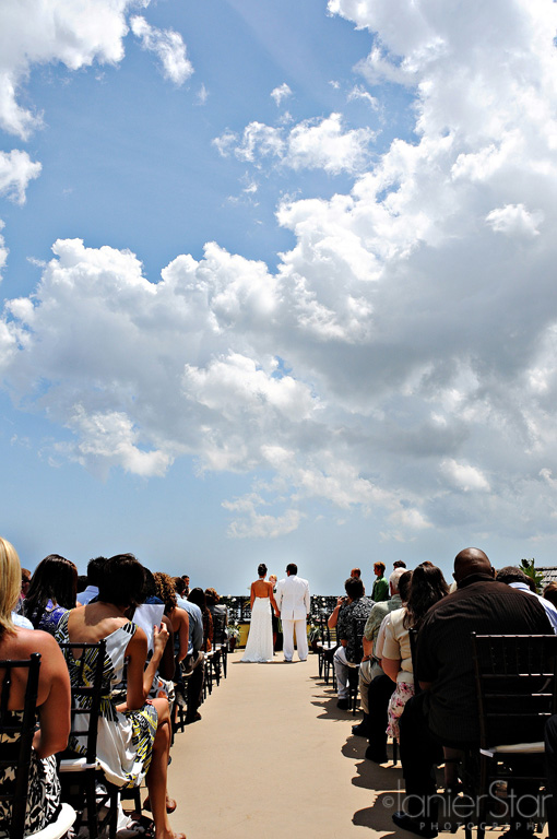Wedding ceremony under a bright blue sky with clouds and guests