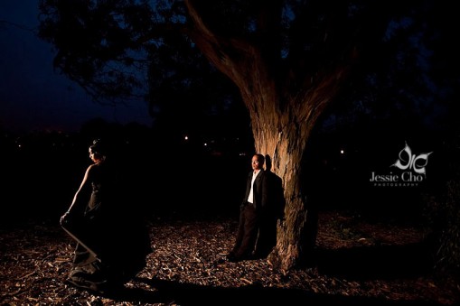 Couple posing next to a tree in a dark, romantic setting
