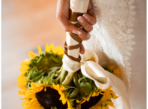 Bride holding a sunflower bouquet with ribbon detail at her wedding