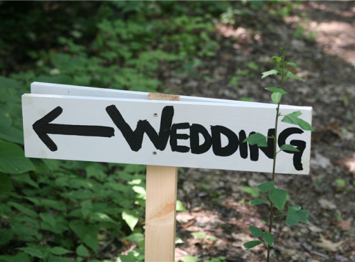 Wedding sign in the forest pointing the way to the ceremony