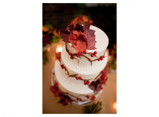 Three-tiered wedding cake with fall-themed decorations and leaves