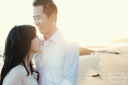 Asian couple smiling lovingly on a sunny beach