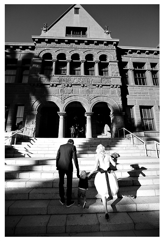 Newlyweds walk steps of city hall with their child