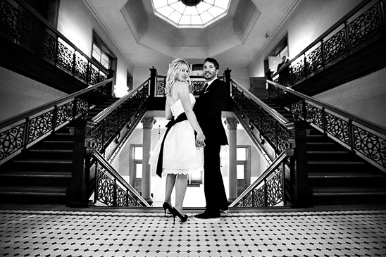 Bride and groom on grand staircase in black and white