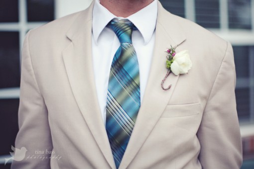 Groom in tan suit blue plaid tie and white flower boutonniere