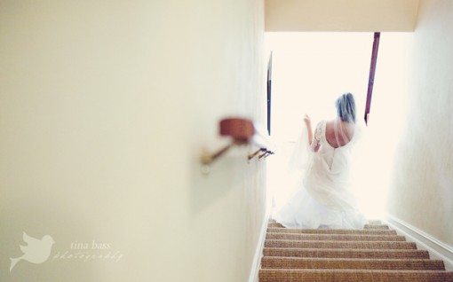 Bride walking up stairs towards light in her wedding dress
