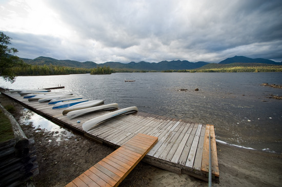 Canoes docked at a serene lake with mountain view