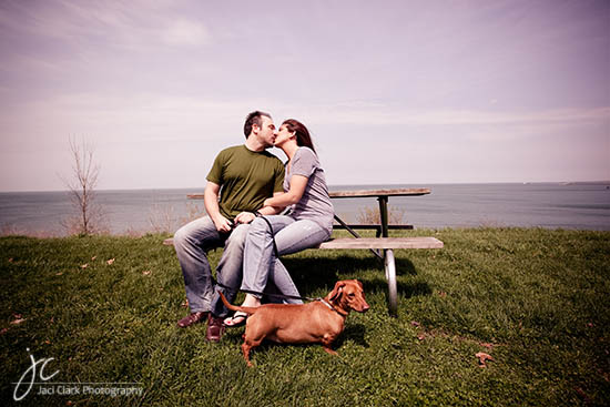 Couple kissing on bench with dog in a park near the sea