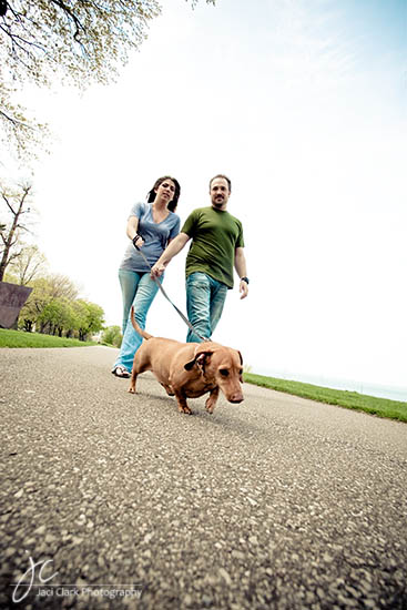 Couple walking a dog on a path, enjoying a sunny day