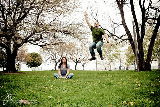 Couple enjoying nature, man jumping in park while woman watches