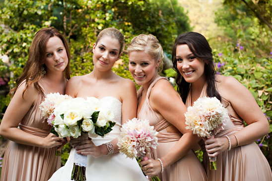 Bride and bridesmaids with bouquets smiling for a wedding photo