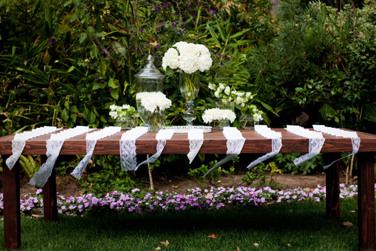 Wooden table decorated with lace and flowers in a garden setting