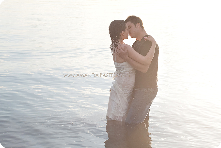 Romantic couple embracing and kissing in the water during sunset