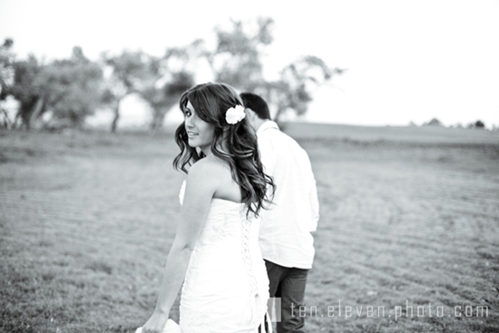 Bride in dress with flower in her hair smiling over her shoulder
