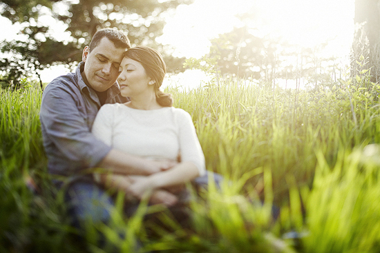 Couple embraces in a sunlit field, enjoying a moment of togetherness