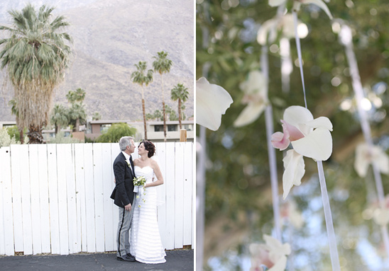 Couple embraces in front of a white fence, decorated with orchid flowers