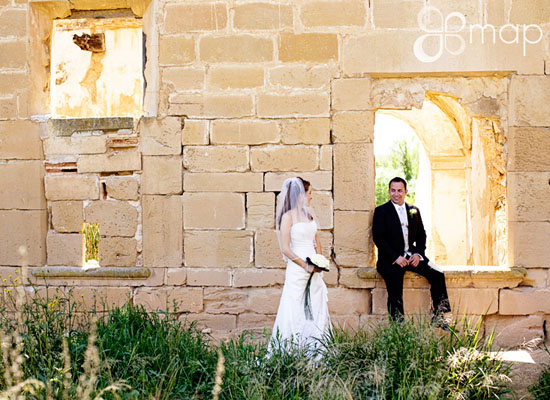 Bride and groom posing in a stone structure on their wedding day