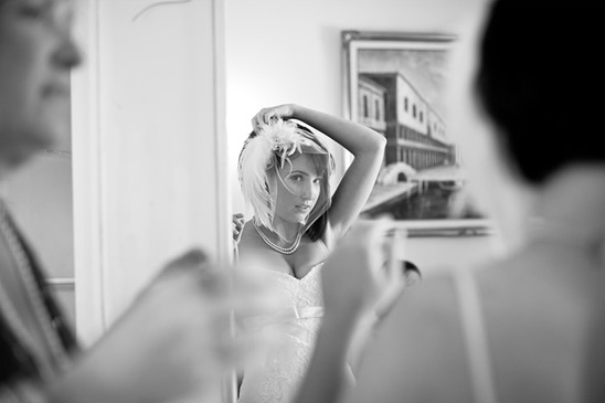 Bride adjusting headpiece looking in mirror, black and white