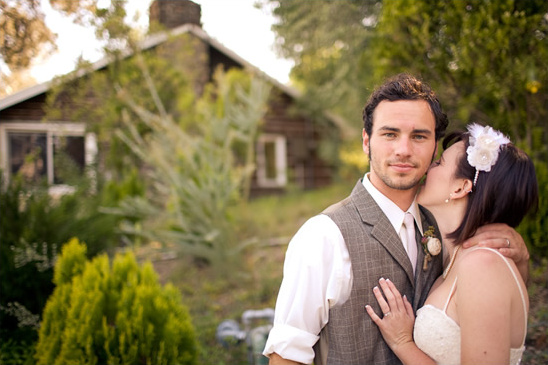 Newlyweds share a tender kiss outdoors, celebrating their wedding day