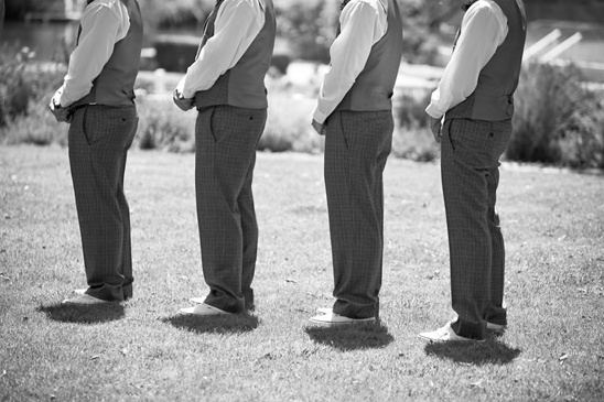 Four men in formal attire standing on the grass in black and white