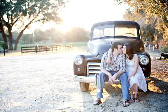 Romantic couple kissing in front of vintage truck at sunset