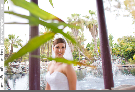 A radiant bride poses by a fountain on her wedding day, outdoors