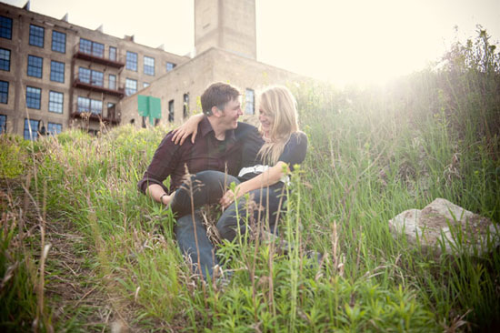 Couple laughing together in a field with a building in the background