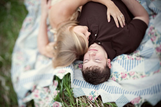Couple cuddling on a blanket in the grass, romantic moment of affection