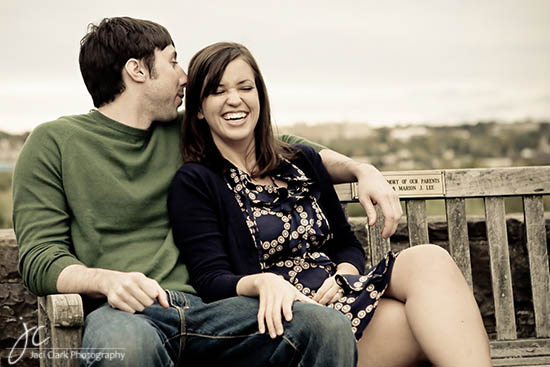 A happy couple is sitting and laughing together on a park bench