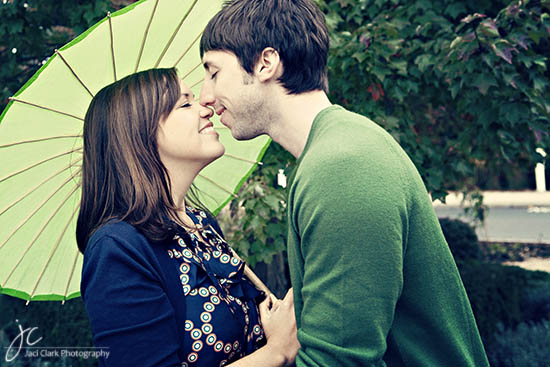 Couple about to kiss under a green umbrella, romantic moment