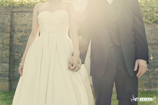 Bride and groom holding hands on wedding day with a bright sunlight