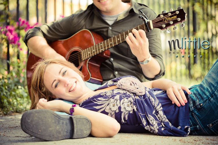 Couple playing guitar outdoors smiles