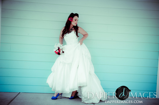 Bride in white wedding dress poses against blue wall