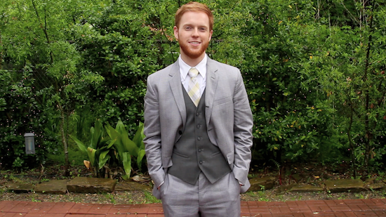 Redhead man in gray suit and vest smiling outdoors