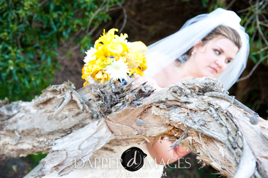 Bride holding yellow wedding bouquet near tree