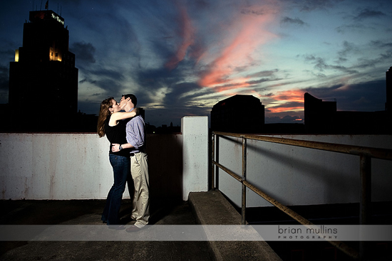 Couple kissing on rooftop at sunset cityscape view